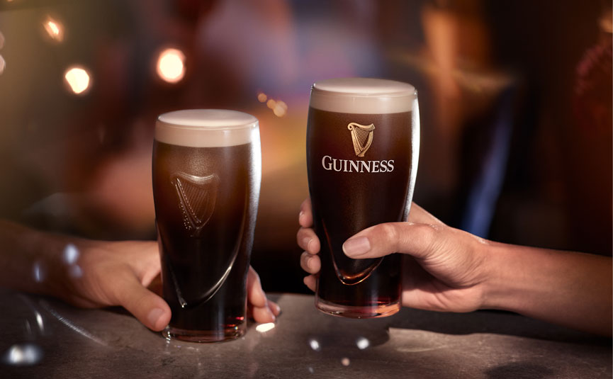 Two hands holding pints of Guinness