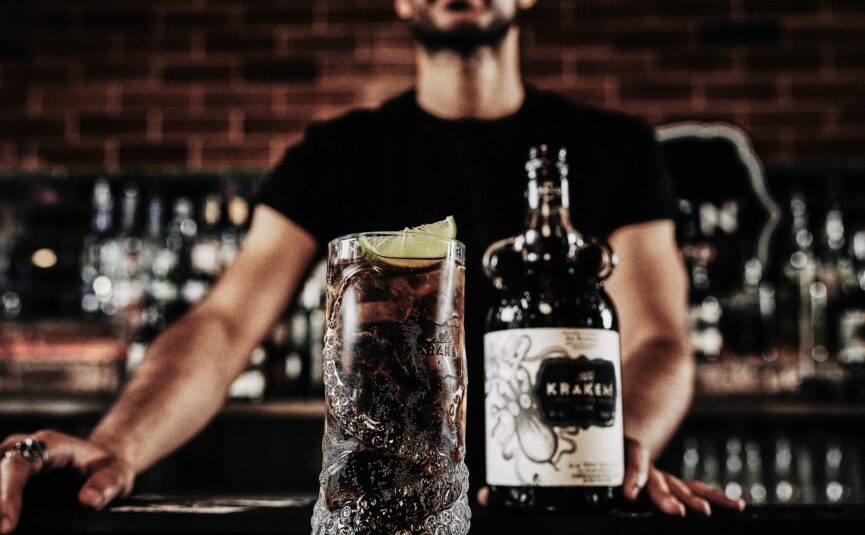 A bottle of Kraken Black Spiced Rum and a cocktail on a bar