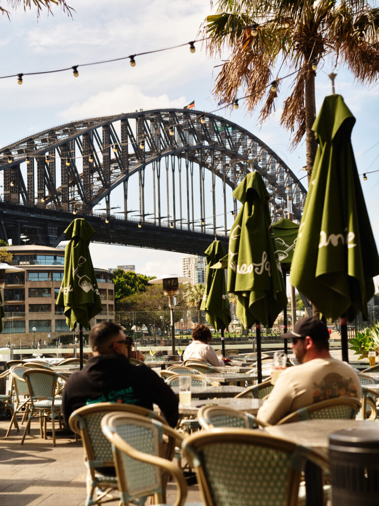 People dining with the Sydney Harbour bridge in the background.