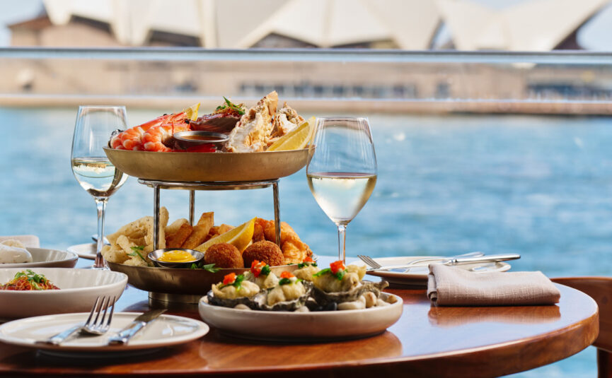 A waterfront dining area with the Sydney Opera House in the background.