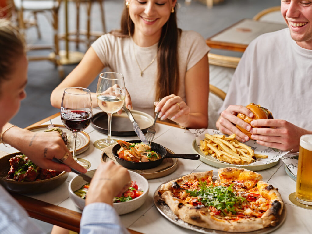 Smiley people around a table with a selection of pub classic meals.